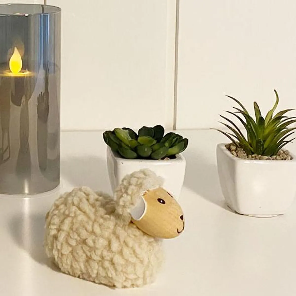 Sau av tre med beige ull, liggende
